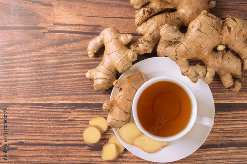 Hot ginger tea with ginger root and slice on wooden table. top view photo