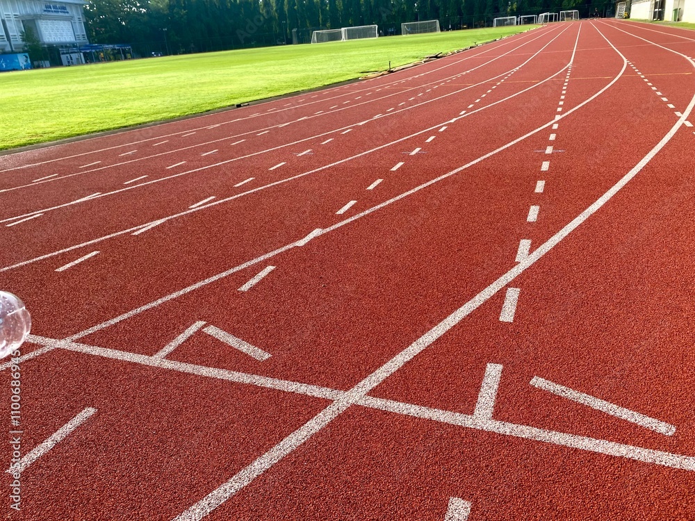 Fototapeta premium Red athletics track featuring crisp white lane markings and numbered lanes 