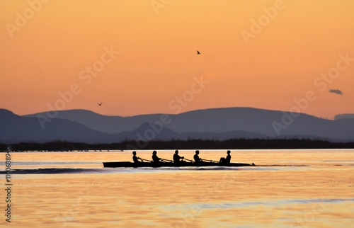 Obraz na płótnie Silhouette of persons rowing on a boat at sunset w salonie