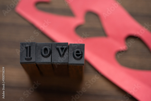 Tipos formando la palabra Love con recortes de corazón en el fondo photo