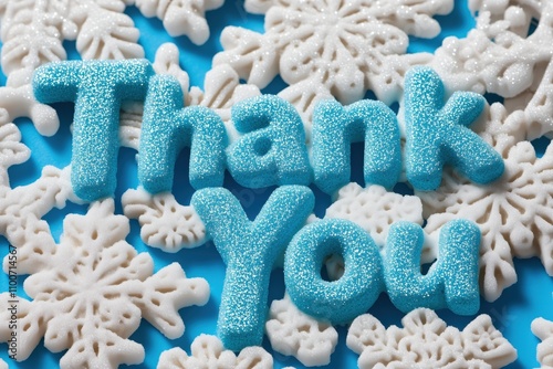 Thank You message formed with sparkling blue and white snowflake candies on a bright blue background