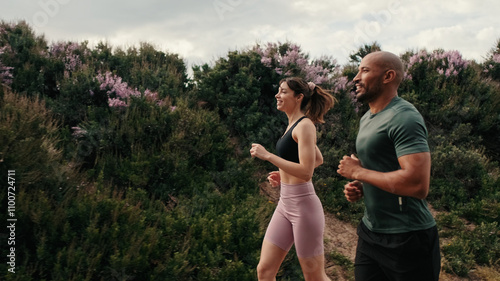 Side view of jogging multiethnic woman and man enjoy their outdoors workout in summer. Team sports. Couple goals and motivation. Happy fit people are cheerfully doing sports