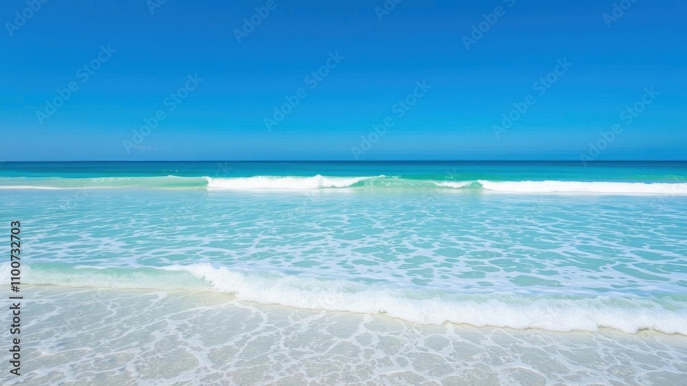 Fototapeta premium Soft blue ocean wave gently rolling onto a beautiful sandy beach on a sunny day, summer, relaxation