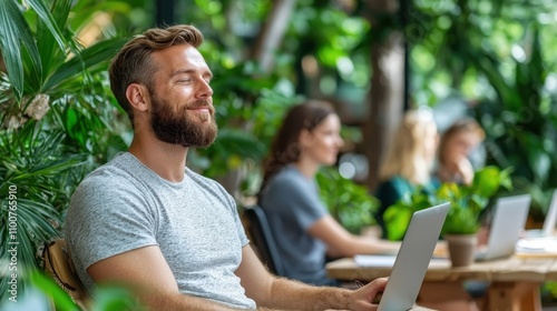 Bearded male professional working remotely on laptop computer in peaceful outdoor coworking space with greenery and natural elements  Concept of modern flexible