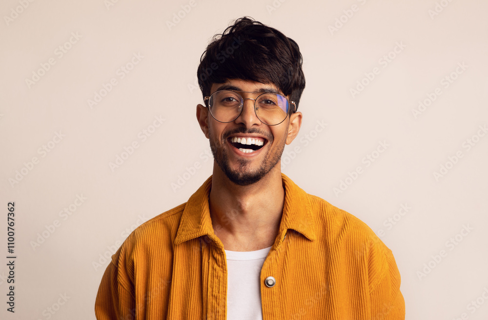 Obraz premium Closeup portrait of happy bearded arabic guy wearing glasses laughing at camera over grey studio background, copy space. Handsome middle-eastern young man in casual showing positive emotions