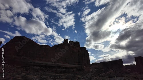 View from vehicle driving by the Tower of Babel in Arches National Park tracking the red rock cliff while moving by. photo