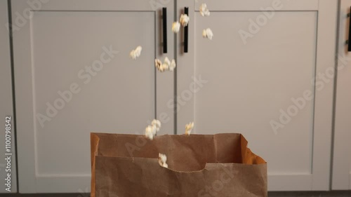 Slow motion popcorn falling into paper bag