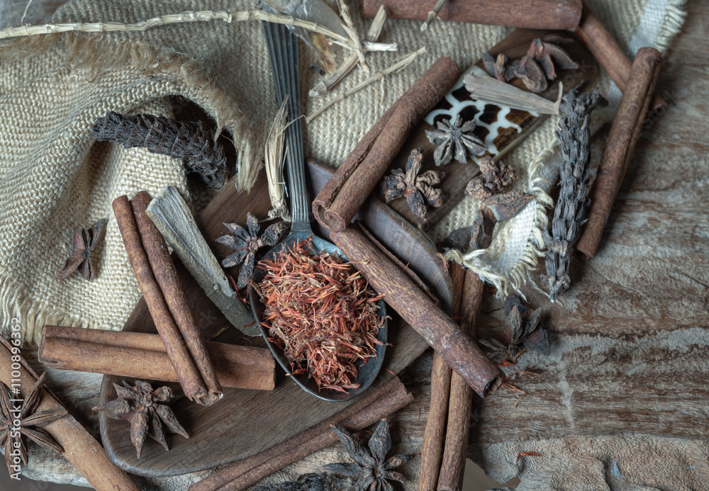 Safflower on spoon with Cinnamon, Star anise and Dried Prunella Vulgaris (Xia ku cao) on old rustic wooden background. Various spices and Natural herbs medicine concept, use it as your Wallpaper,