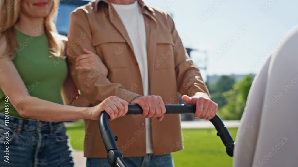 Couple hands carrying stroller newborn child in park closeup. Pair strolling Couple hands carrying stroller newborn child in park closeup. Pair strolling