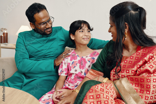 Multiracial family sitting together in a cozy living room wearing traditional festive attire smiling and talking to each other creating a warm and joyful atmosphere photo