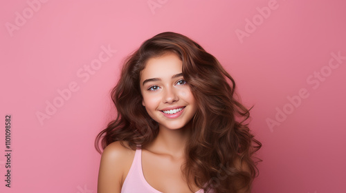 Portrait of smiling latin american teenage girl with pink background.