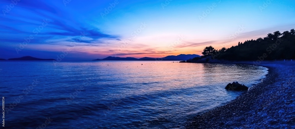 Fototapeta premium Serene twilight over calm blue sea with gentle waves and vibrant sky at dusk reflecting nature's beauty and tranquility.