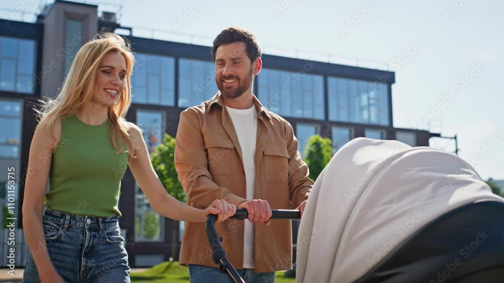 Young couple pushing stroller crossing near apartment closeup. Happy parents