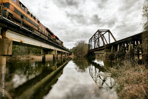 A freight train passes over a bridge spanning the water. photo