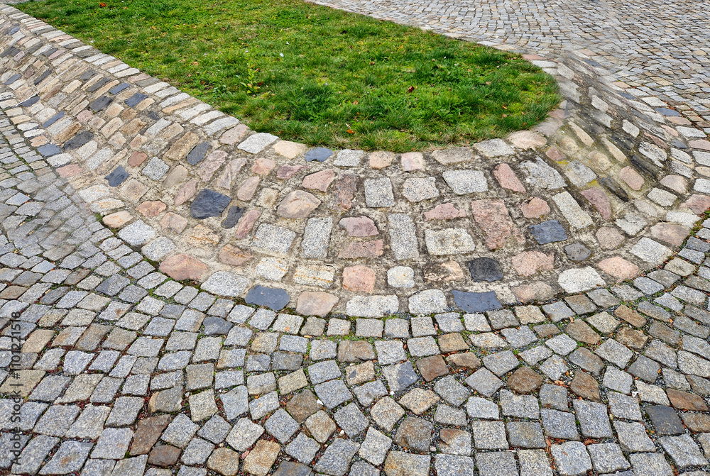 Fototapeta premium A paved island on a raised hill with a lawn on top. It separates lanes and protects the grass from winter salting.