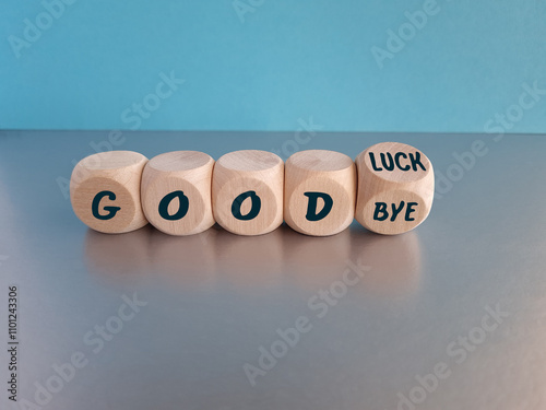 Good luck or goodbye symbol. Concept words Good luck or Goodbye on beautiful wooden cubes. Beautiful grey table, blue background