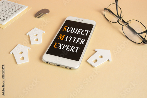 Concept words SME, subject matter expert concept on the mobile phone screen. Beautiful beige background. Glasses, miniature houses, coins. Business, SME, subject matter expert concept.