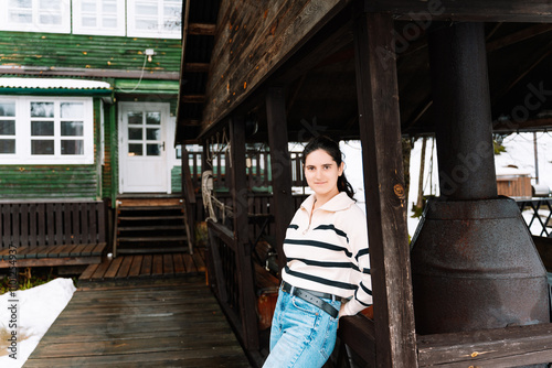 young woman near a gazebo with grill stands in front of a wooden house photo