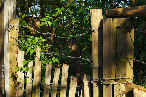 Barbed wire on a rundown wooden fence used as a deterrent to burglars to protect a property home