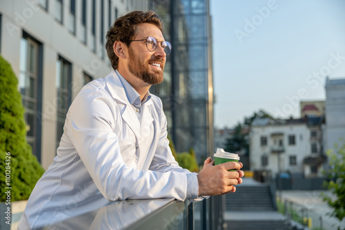 Ginger good-looking doctor having coffee in the morning and looking contented