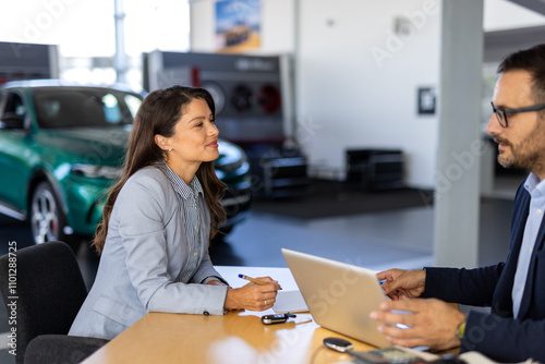 Beautiful woman Buying New Car Signing Papers With Dealer Man Standing In Auto Dealership Store.