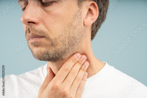 Unwell man holds neck feels sharp throat pain, inflammation from acid reflux, swollen lymph nodes due to illness. Viral or bacterial infections, tonsillitis, dry air, exposure to smoke or allergens. photo