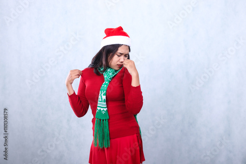 woman charm wearing red sweater party dress with Santa hat and scarf, both hands pinching clothes smelling uncomfortable body odor, celebrating christmas and new year isolated on white background photo