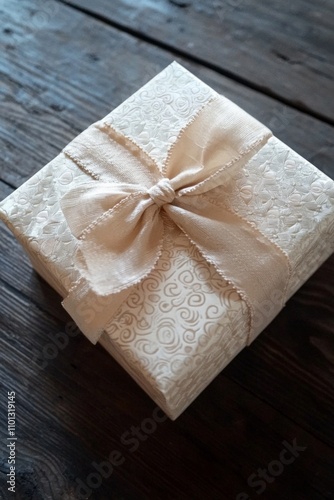 A beautifully wrapped gift box with ribbon on a dark wood background. 