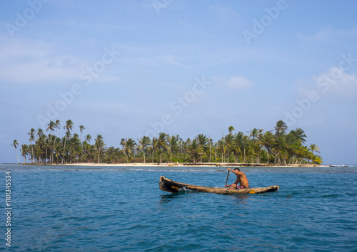 Panama, San Blas Islands, Mamitupu, Kuna Indian Man In A Traditional Canoe In Front Of An Island photo