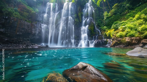 photograph of Jungle waterfall cascade in tropical rainforest with rock and turquoise blue pond. Its name Banyumala because its twin waterfall in mountain slope photo