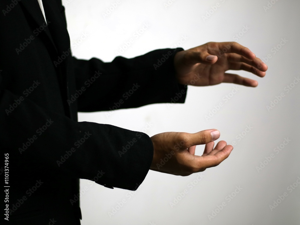 Obraz premium A confident hand in a sleek black suit gestures animatedly, illustrating a strategic business concept such as focus, collaboration, goal setting, time management, networking, emphasizing collaboration