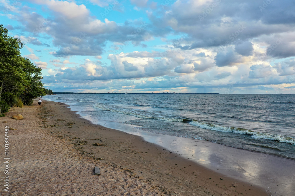 Serene beach walk during sunset near calm waters and scattered clouds in a tranquil coastal setting Serene beach walk during sunset near calm waters and scattered clouds in a tranquil coastal setting