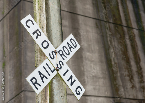 Close-up of a Railroad Crossing sign in front of a grungy industrial looking wall, USA photo