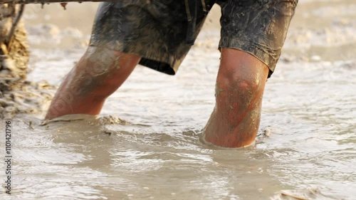 An harrow's teeth in muddy water as a farmer installs it to a hand tractor, traditional tool and equipment in rural rice farming, rotavator blade photo