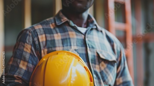 Portrait of a smiling male construction professional with an all-access pass for a conference, holding a safety helmet in a workshop setting