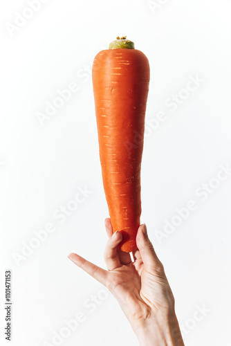 Hand holding carrot on white background, word carrot in top left corner photo