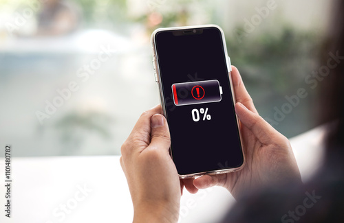 Close-up view of woman using mobile phone with battery died notification screen Zero percent remaining. concept of emergency backup battery, Power bank