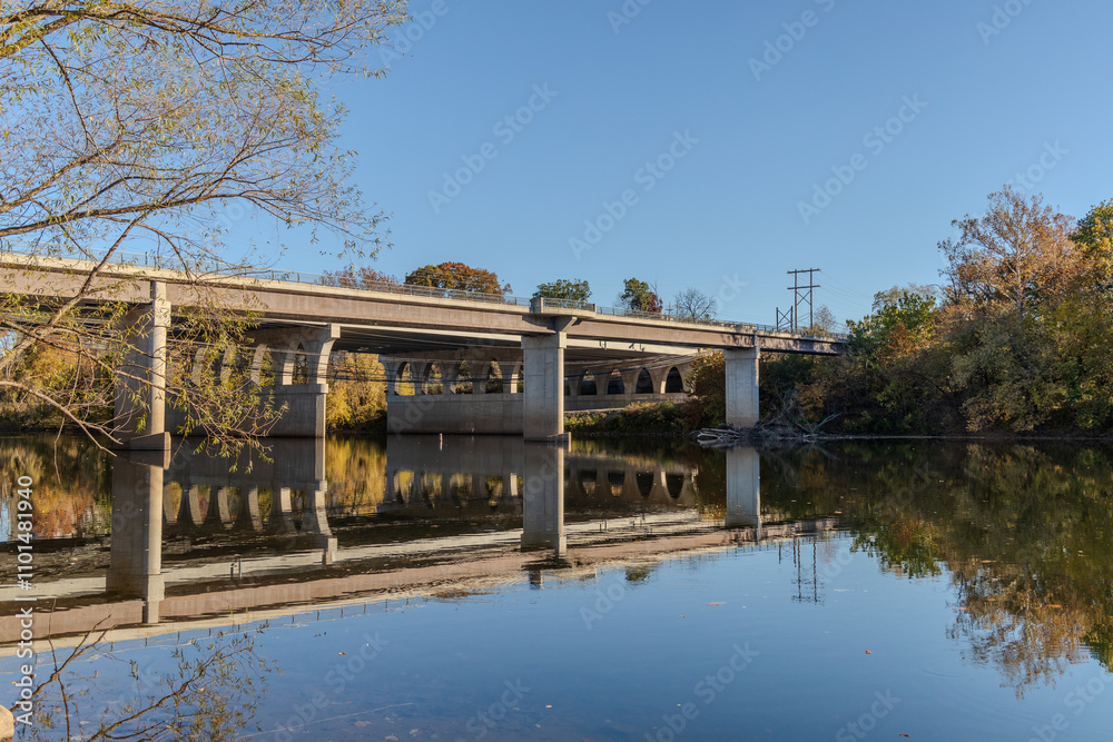 Fototapeta premium A bridge spans a river with a calm, reflective surface
