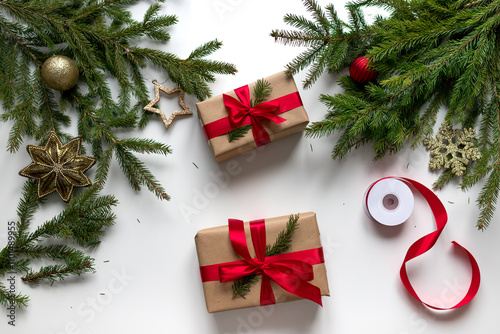 christmas gifts in craft paper and tied with a red ribbon. Christmas gift wrapping using eco-friendly materials and pine branches.