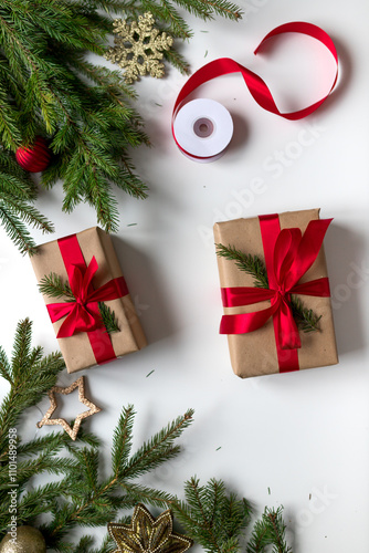 christmas gifts in craft paper and tied with a red ribbon. Christmas gift wrapping using eco-friendly materials and pine branches.