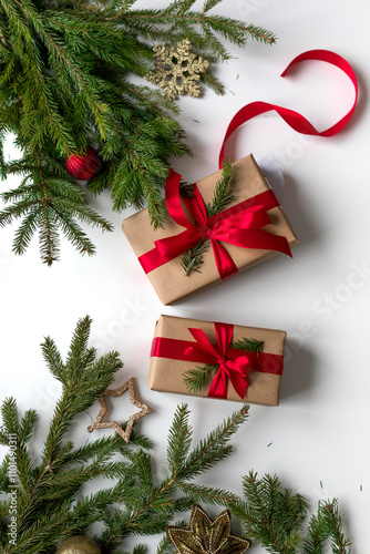 christmas gifts in craft paper and tied with a red ribbon. Christmas gift wrapping using eco-friendly materials and pine branches.