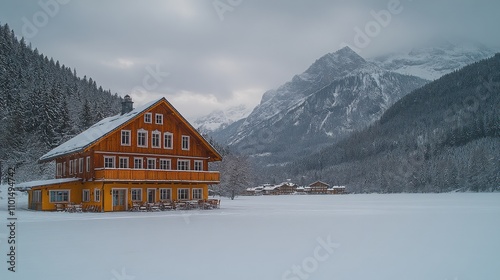 A serene winter landscape featuring a wooden house surrounded by snow and mountains.