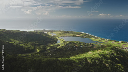 Breathtaking aerial view Moorea island in French Polynesia, green mountains forest, small village, turquoise ocean lagoon, lakes, and airport runway under blue sunny sky. Drone shot travel background