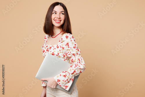 Side view young happy fun smiling IT woman wears white top casual clothes hold closed laptop pc computer look aside on area isolated on plain pastel light beige background studio. Lifestyle concept. photo