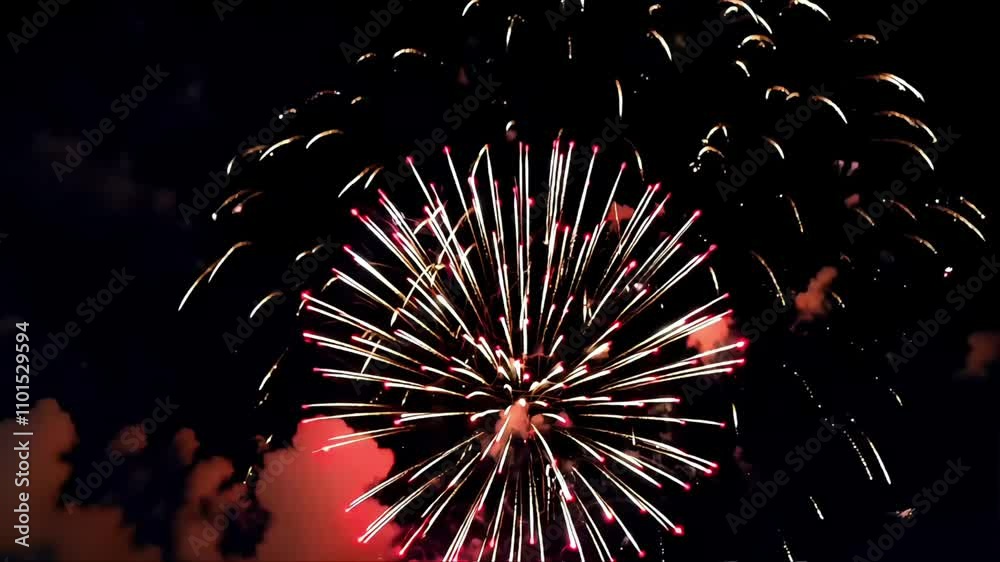Bright red fireworks illuminate the night sky, creating a vibrant display during a city celebration. Spectators enjoy the spectacular show, cheering and clapping