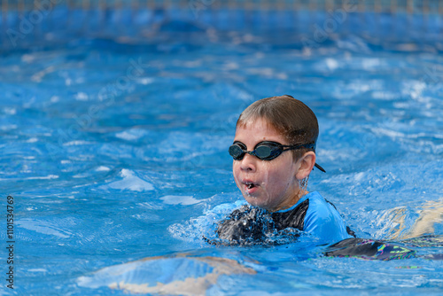 Close-up action portrait of a young swimmer while swimming breaststroke style in the swimming pool