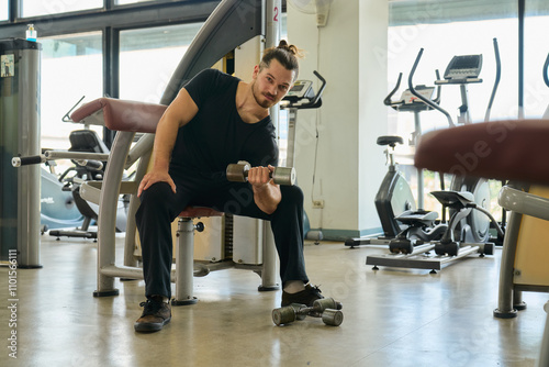 A caucasian man in black shirt is working out with wieght training machine for good health in sport gym. photo