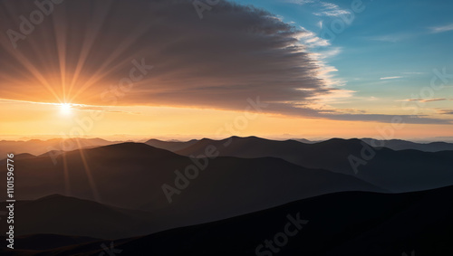 Sunset over mountain peaks with dramatic sky and shadows.