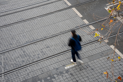 Motion blurred pedestrian crossing tram tracks seen from above photo