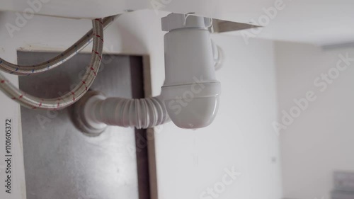 A plumber unscrews the siphon sump under the sink. Repair and eliminate leaks in the sink